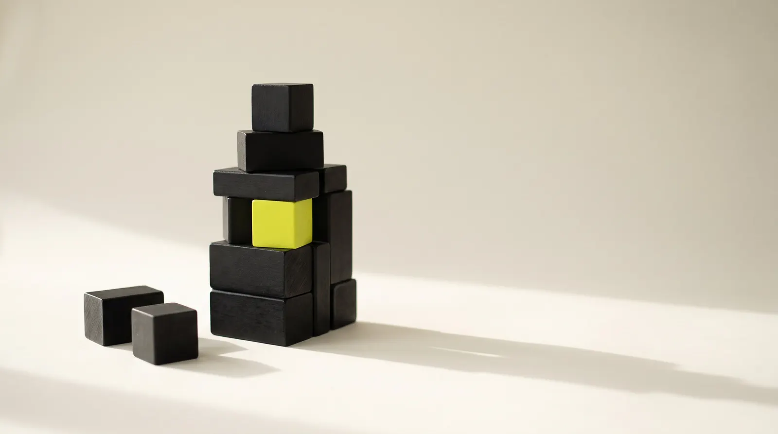 Black wooden blocks stacked into a tower with one lime block in the middle: a site assembled piece by piece.