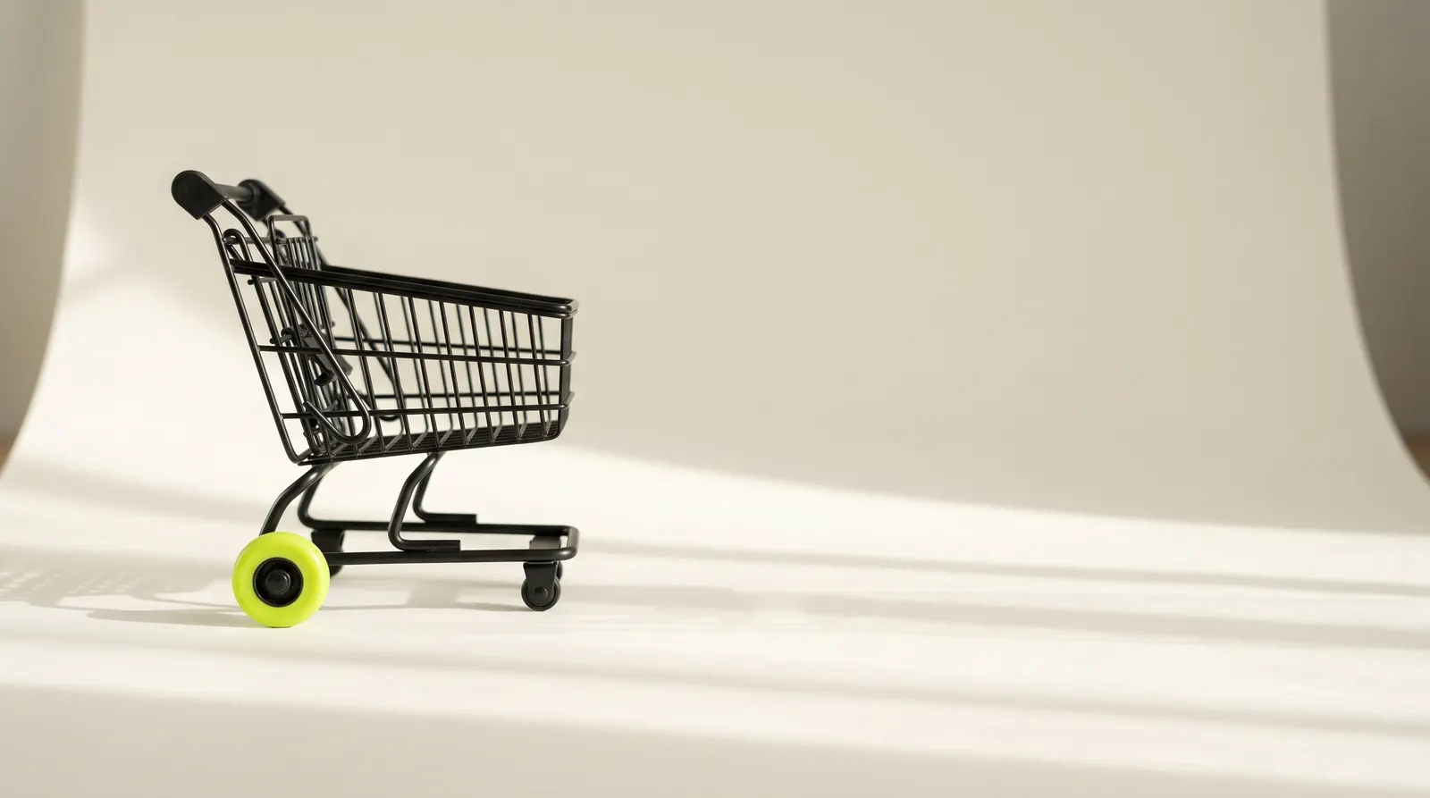 Black wire shopping cart with one lime wheel on a paper backdrop: a store ready to take orders.