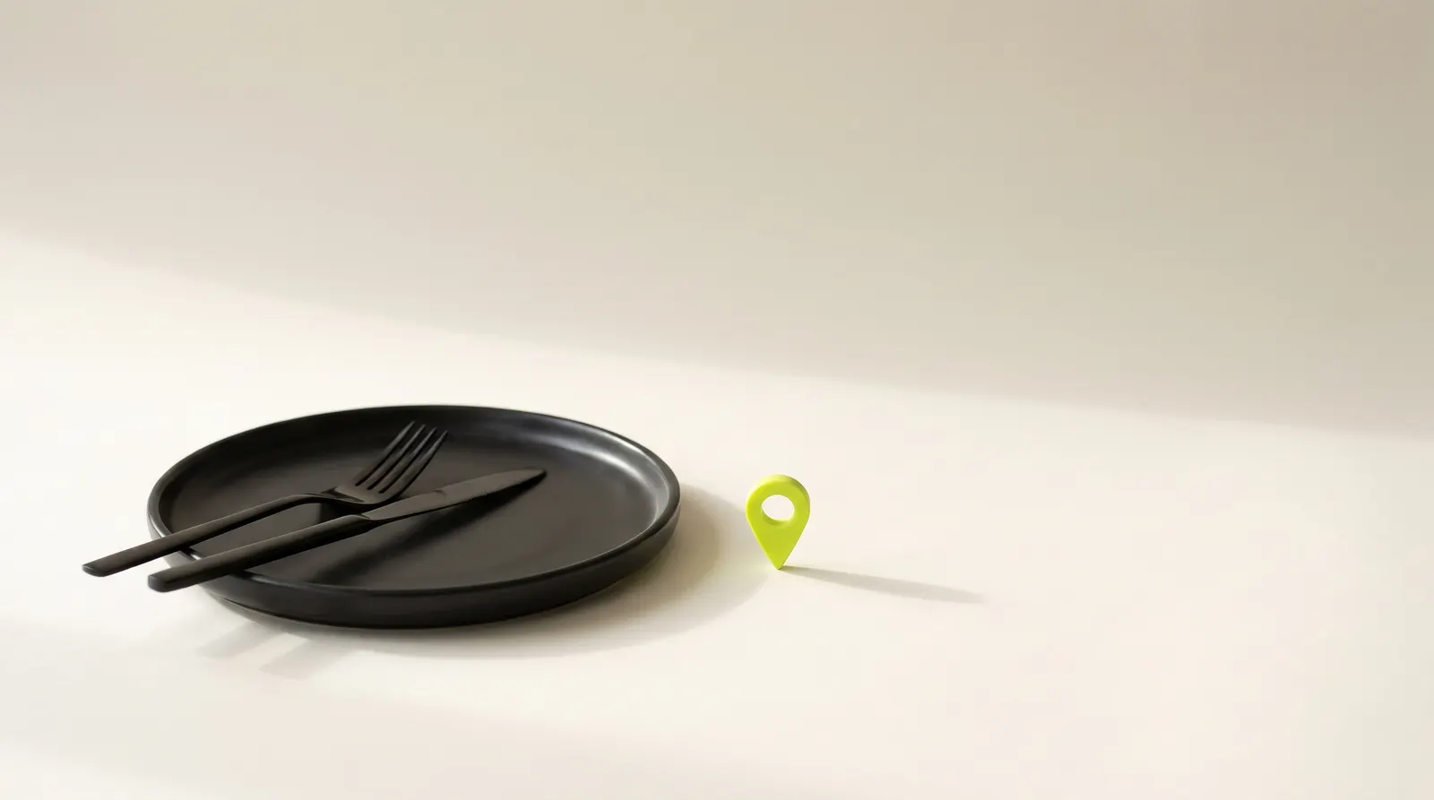 Empty black dinner plate with a fork and knife next to a small lime map pin, like a restaurant marked on the map.