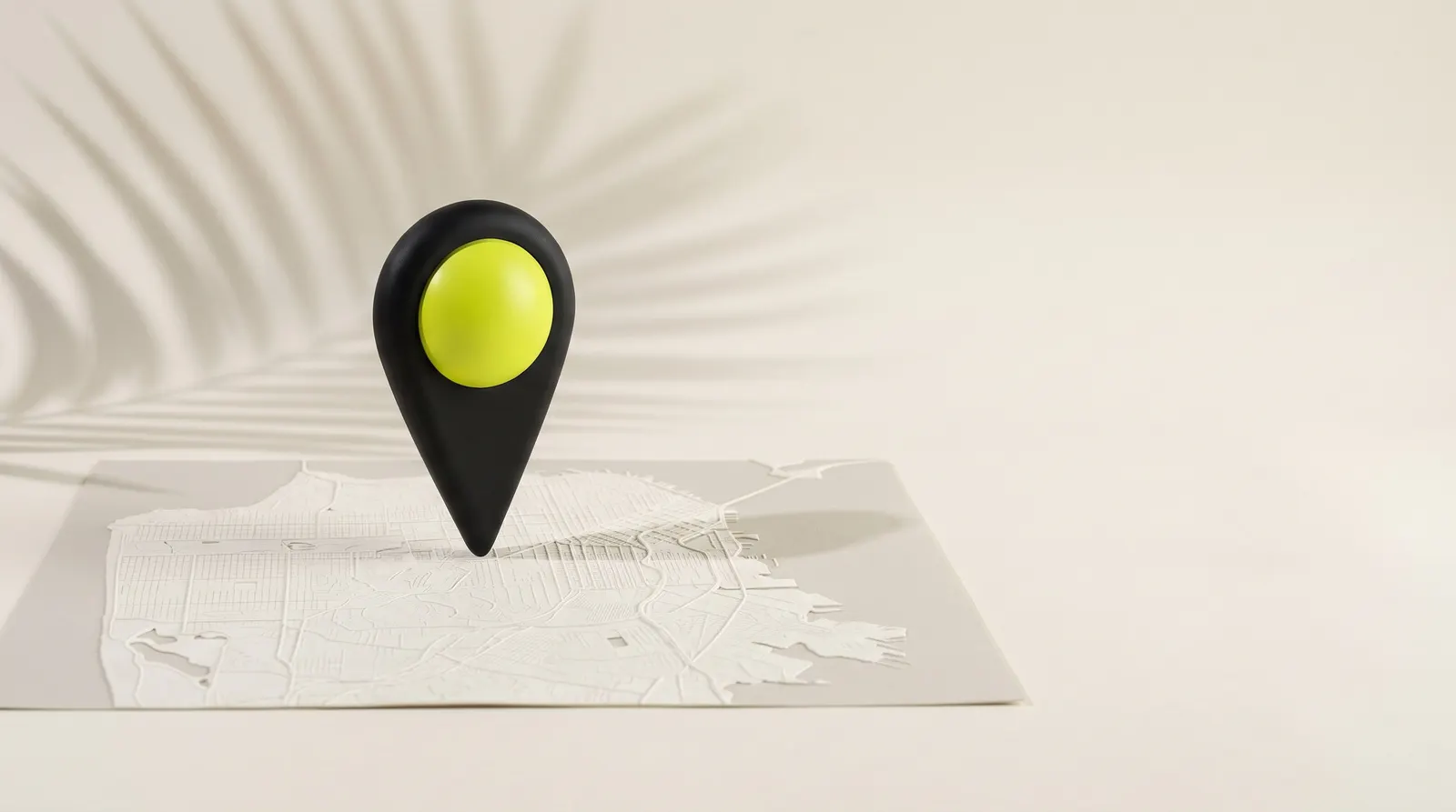 Marcador de mapa negro con cabeza verde lima sobre un mapa en relieve, con la sombra de una hoja de palmera.